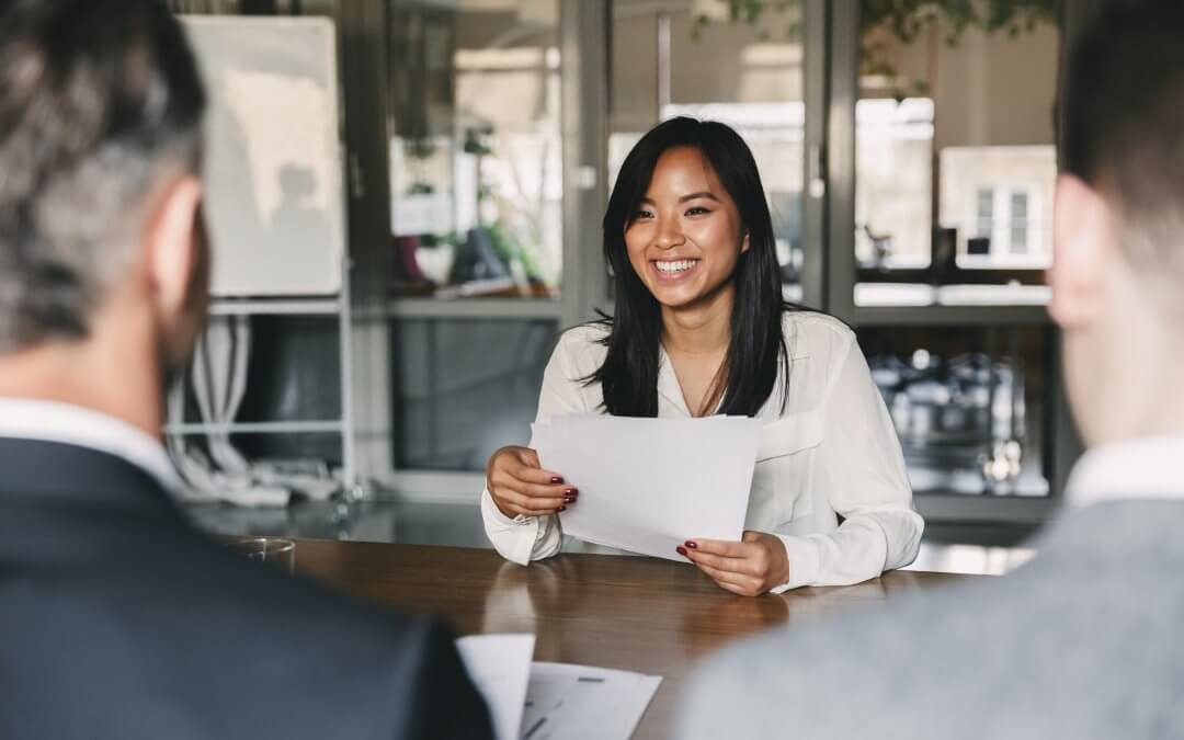 Business, career and placement concept - young woman smiling and holding resume, while sitting in front of directors during corporate meeting or job interview